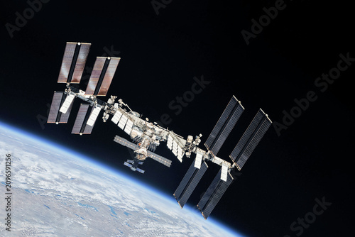 International Space Station floats above Earth's blue oceans and white clouds. Elements of this image furnished by NASA