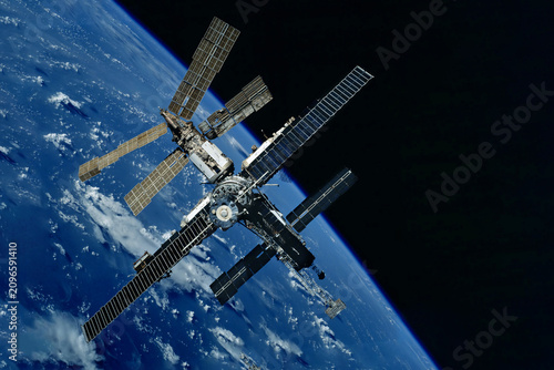 International Space Station floats above Earth's blue oceans and white clouds. Elements of this image furnished by NASA