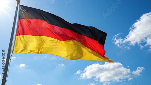 German flag waving against a blue sky with clouds