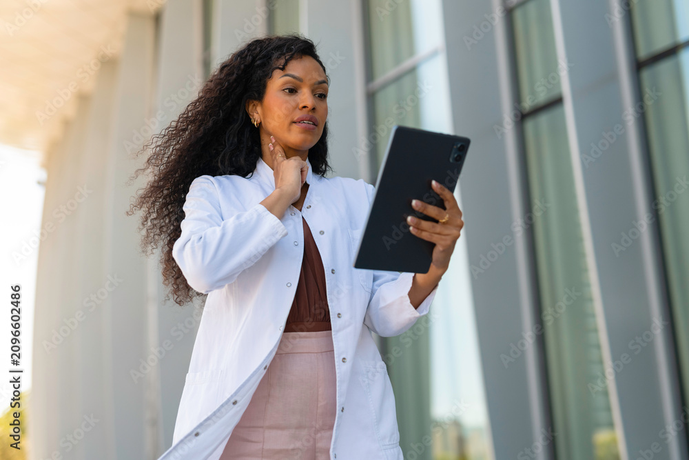 Fototapeta premium Doctor palpating neck while using digital tablet for telehealth video consultation