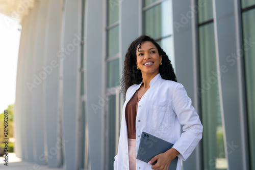 Female doctor holding digital tablet smiling outdoors