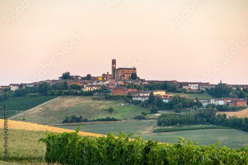 Hilltop Village with Historic Church and Vineyards in Piedmont, Italy, at Sunset