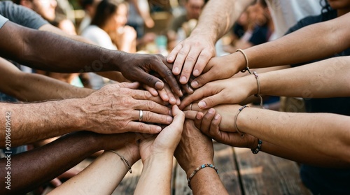 Diverse group of people stacking hands together showing unity and teamwork in a close up shot