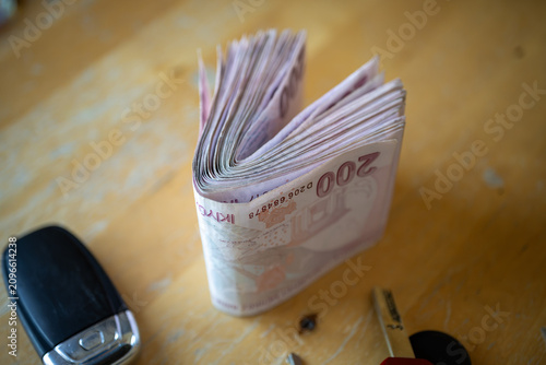Turkish Lira banknotes standing on table near car key. Folded paper currency representing financial transaction and automotive purchase budget planning for banking economy