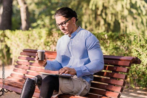 Latino man with prosthetic leg using tablet in park