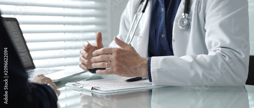 Photos Doctor wearing a lab coat and stethoscope, using hand gestures to explain medica