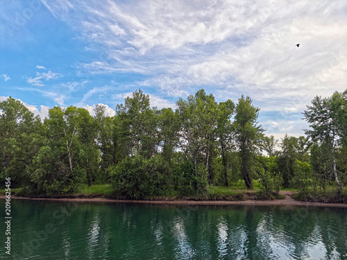 Landscape features the calm waters of the river and lush vegetation along the banks. Such places are often used for outdoor activities and tourism.