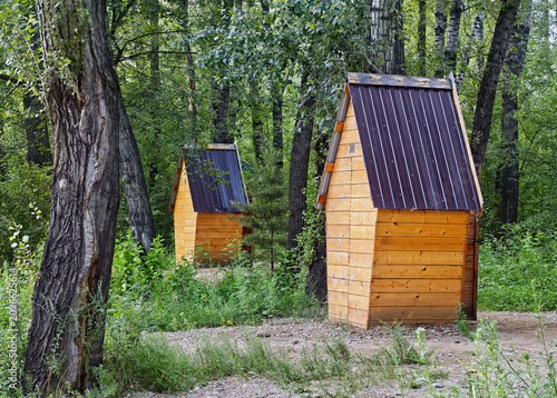 Wooden toilets for a summer cottage or park, with a dark gabled roof.
