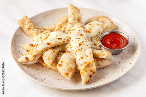 Brick oven bread sticks with ketchup in a light environment