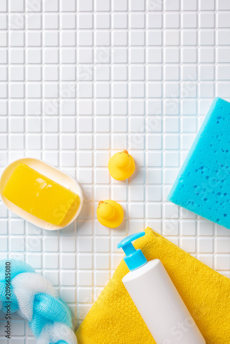 Top view of baby bath accessories and rubber ducks on white mosaic tiles with top copy space