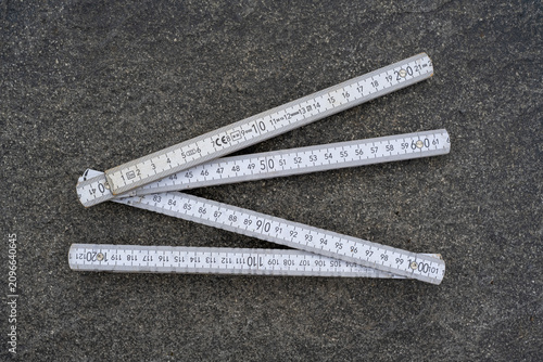 фотографія White Folding Ruler Fully Extended, Lying on Patio Paving Slabs, Construction Me