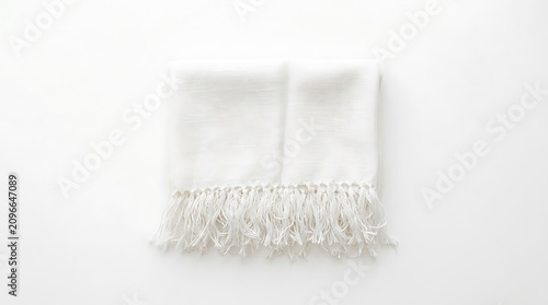 Folded white scarf with fringed edges, isolated on a plain white background, soft textile texture, minimalist clothing accessory product shot