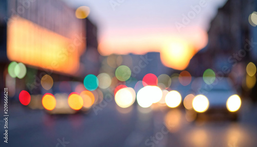 Blurred city street traffic lights at sunset creating beautiful colorful bokeh circles on a dark urban road background setting