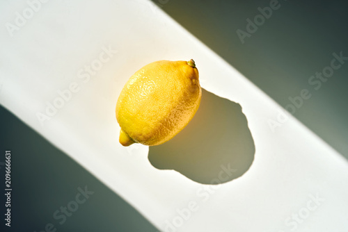 Bright yellow lemon casting long shadow under natural light