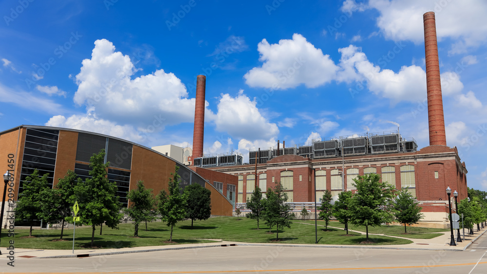 Fototapeta premium Industrial powerhouse building with tall brick chimney against blue sky