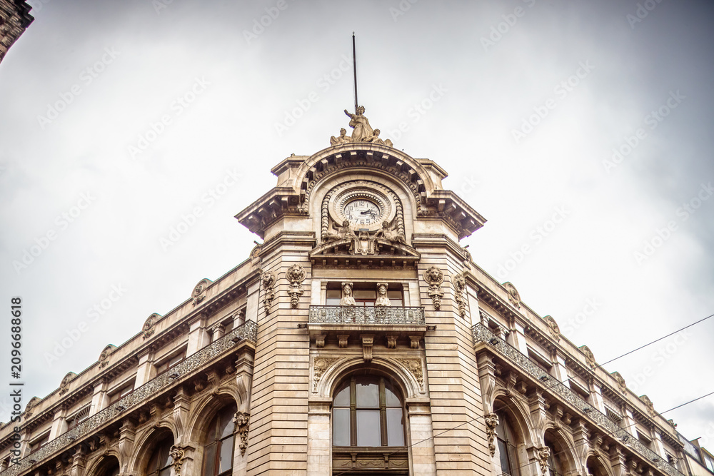 Fototapeta premium White building with neoclassical architecture, clock and sculptures on its facade, 