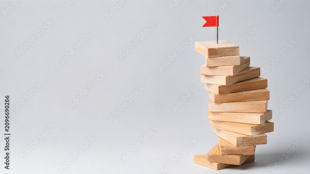Obraz premium Red flag pin on top of stacked wooden block tower. Concept of career achievement, business goal leadership, and overcoming startup obstacles.
