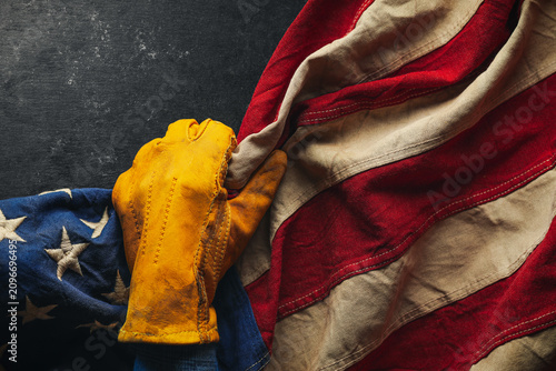 Worn work glove pulling back the American flag. Symbolic of blue collar workers, USA manufacturing, pride in products Made in United States of America, or to celebrate Father's day or US Labor Day.