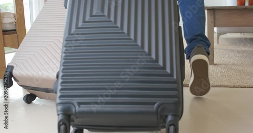 Door opening causing African couple arriving walking into home, pulling black suitcase and tan case