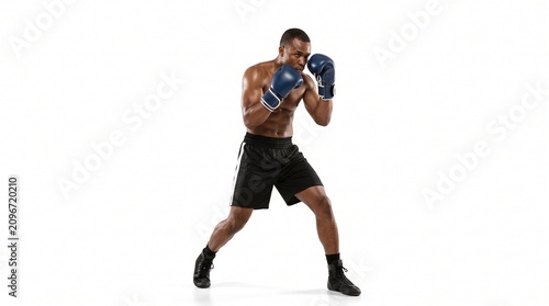 African American boxer in fighting stance wearing blue gloves and black shorts on white background