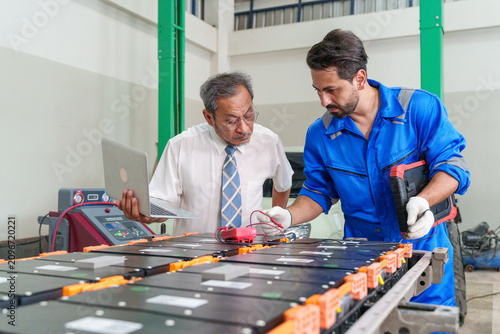Fotografie Technician and engineer inspecting electric vehicle batteries in a repair shop f