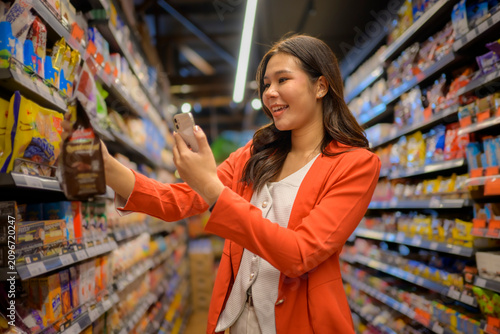 Asian woman shopping comparing product details with smartphone