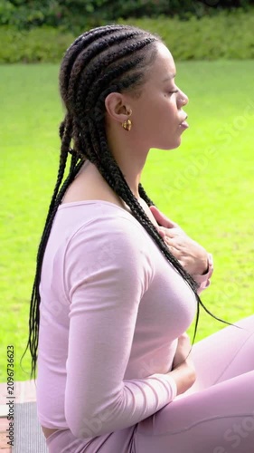 Vertical video: Inhaling woman in pink gear breathing with hands on chest and belly on mat for calm