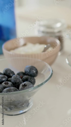 Vertical video: Camera panning bringing bowl, berry bowl into focus on counter showing berries