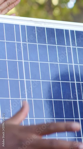 Vertical video: Reaching bare arms sliding and steadying PV panel under trees to mount