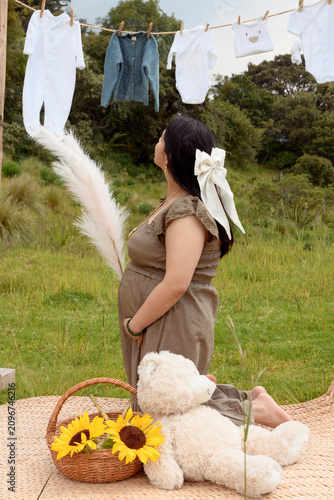 Full Shot of Pregnant Hispanic Woman Kneeling holding Pampas Grass in Meadow Setup
