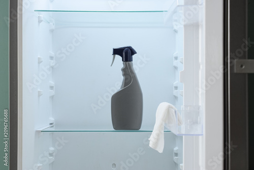фотографія Cleaning spray bottle and white cloth inside an empty refrigerator, household ch