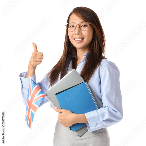Female Asian English teacher with UK flag and notebooks showing thumb-up on w...