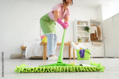 Housewife mopping floor in bedroom, closeup