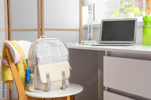 Backpack on chair near desk...
