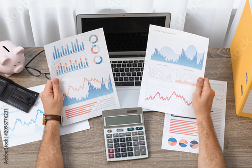 Young man in debt with diagrams at home, closeup