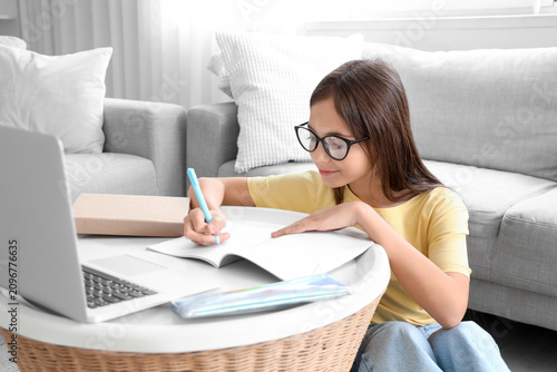 Fotografie Little schoolgirl writing in copybook at home
