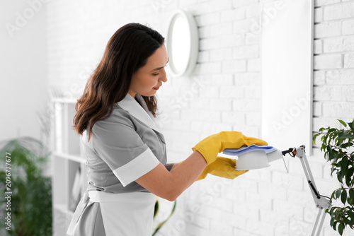Canvastavla Young chambermaid cleaning lamp in office
