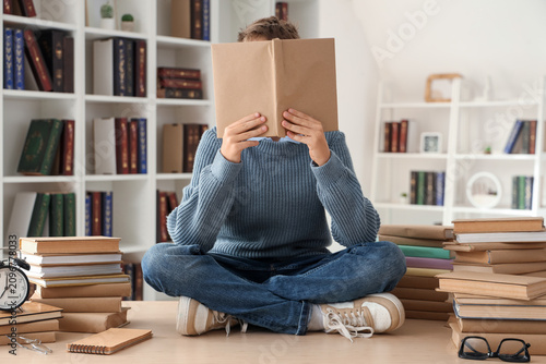 Teenage boy with books sitt...