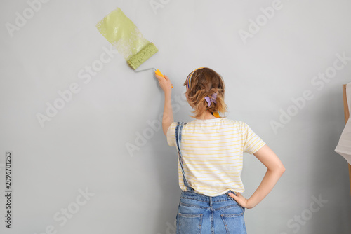 Young woman painting wall d...
