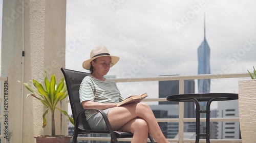 Woman is reading a book at scenic terrace among skyscrapers