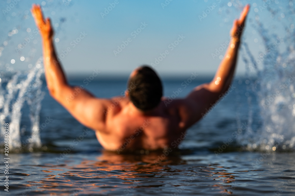Fototapeta premium Water splashes around muscular swimming man. Active water motion shows fitness endurance. Fresh water droplets highlight athletic body. Ocean water activity boosts wellness vitality.