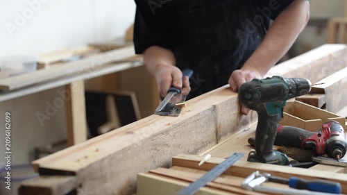 Handwork, craftsmanship and restoration, skilled man carpenter restoring window frame in workshop, renovation master cuts off excess of wooden dowels, connecting parts of planks, progress of repairing