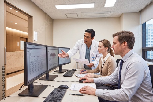Wide view of a multidisciplinary healthcare team reviewing digital patient information and coordinating treatment in a modern clinic, with group discussion and documentary realism