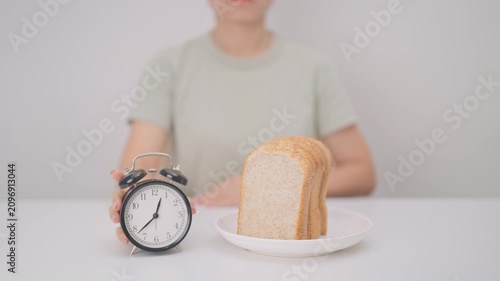 Happy smiling woman with whole wheat bread and alarm clock. concept of intermittent fasting, IF, meal timing, and choosing healthy carbohydrates for a balanced diet and weight loss management