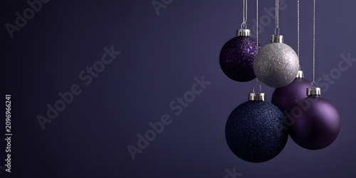 Hanging purple and silver Christmas ornaments on dark background