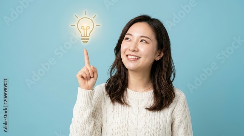 Young asian woman pointing at a glowing light bulb icon
