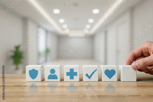Hand placing a wooden block with icons representing health insurance and medical concepts