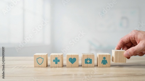 Hand placing a wooden block with medical icons on a desk