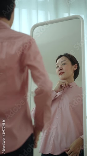 Woman getting dressed in front of a mirror in a modern dressing room. Morning routine capsule wardrobe, personal styling, fashion confidence. Self-care and everyday lifestyle concept.
