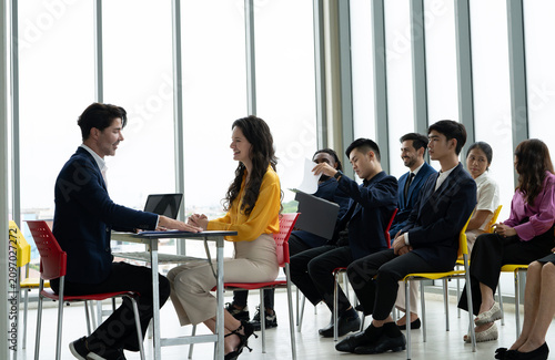 Cuadro en lienzo Job interview between a hiring manager and a smiling candidate while other applicants wait in office